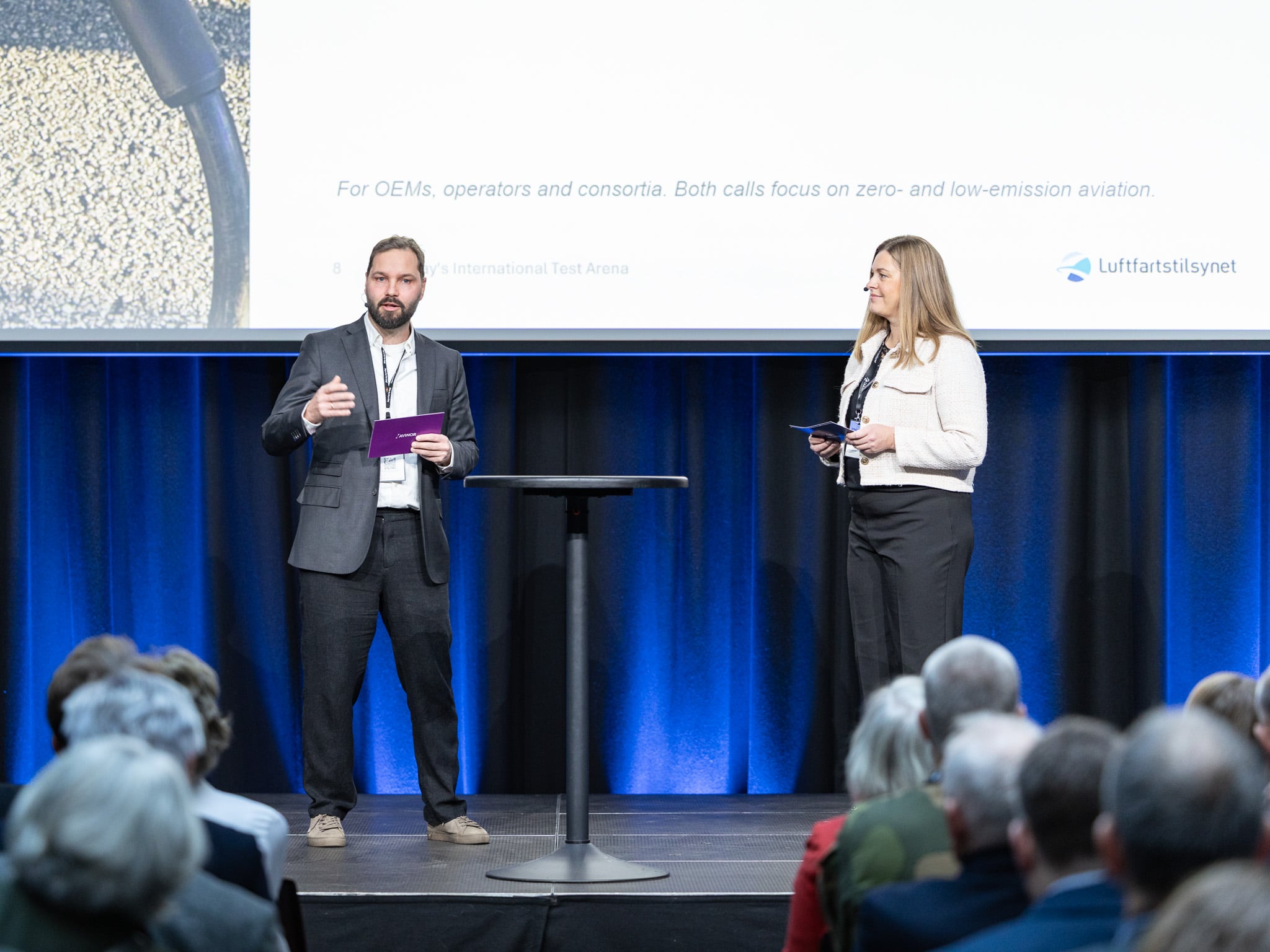 Hans Fridberg og Trine Å. Bernhardsen presenterer fra scenen.